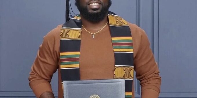 man standing holding SNHU diploma